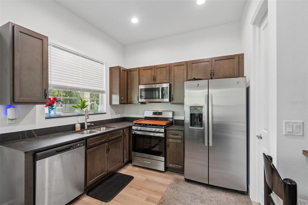 A kitchen features dark wood cabinets, stainless steel appliances, and dark countertops — 12413 HOOKER ROAD, WEEKI WACHEE, FL