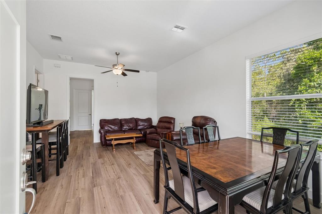 A living and dining area features wood-look flooring, a ceiling fan, and a large window — 12413 HOOKER ROAD, WEEKI WACHEE, FL