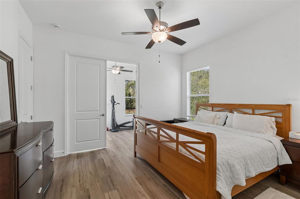 A bedroom with wood-look flooring, a wooden bed frame, and an open doorway to another room — 12413 HOOKER ROAD, WEEKI WACHEE, FL