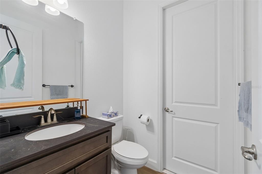 A bathroom features a dark vanity with a white sink, a toilet, and a mirror — 12413 HOOKER ROAD, WEEKI WACHEE, FL
