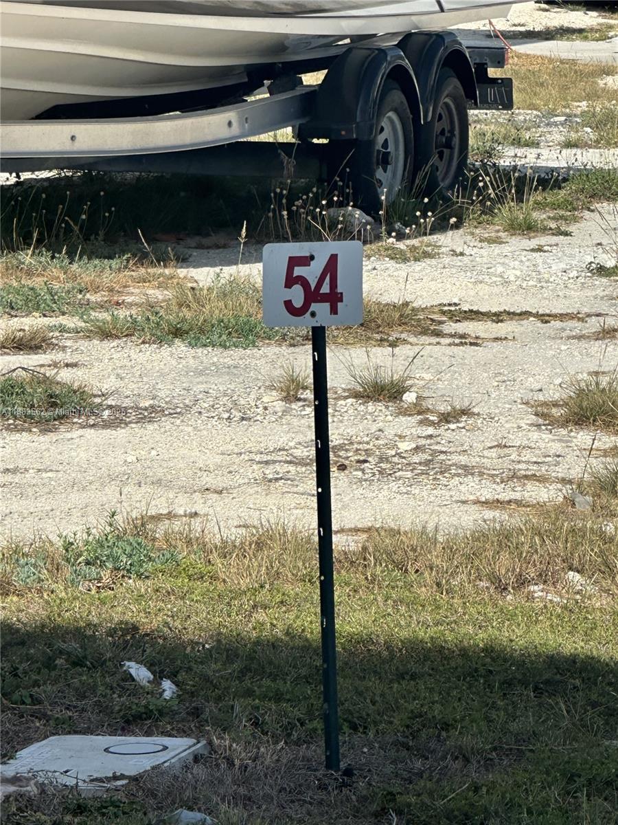 A metal sign with the number 54 stands in a grassy lot near a boat trailer — 94825 Overseas Hwy, Key Largo FL 33037, KEY LARGO, FL