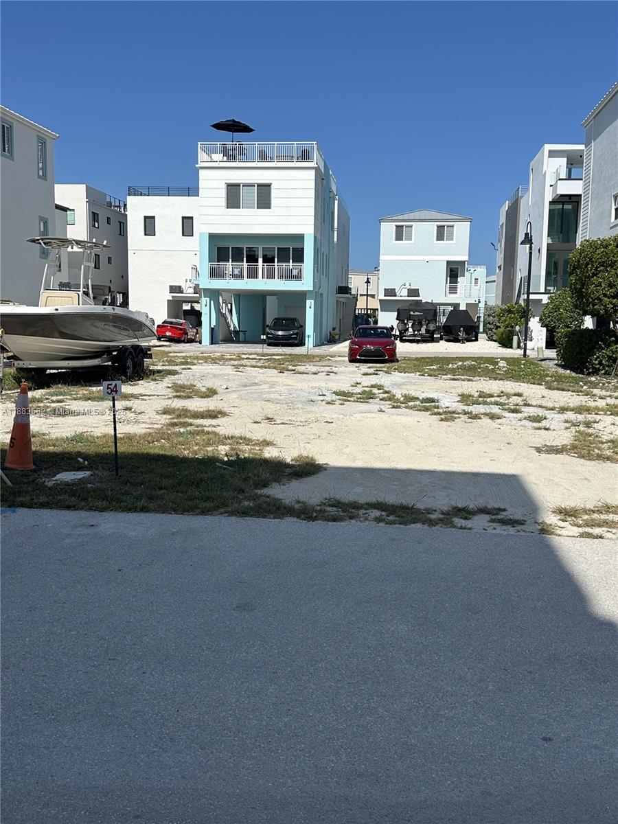 A gravel lot sits between modern multi-story houses with parked cars and a boat trailer — 94825 Overseas Hwy, Key Largo FL 33037, KEY LARGO, FL