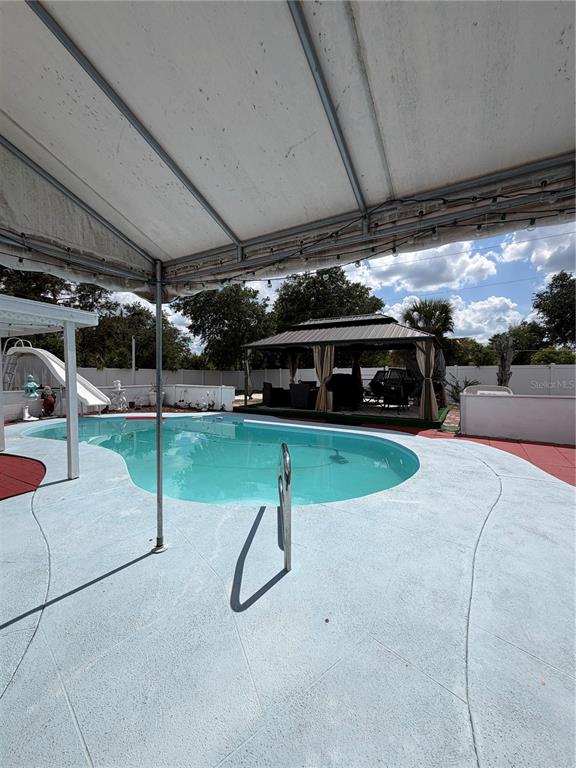 A backyard features a swimming pool with a slide under a large covered patio area — 4162 KINGSBRIDGE DRIVE, ORLANDO, FL