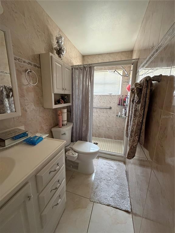 A bathroom features a vanity, a toilet, and a tiled walk-in shower with a curtain — 4162 KINGSBRIDGE DRIVE, ORLANDO, FL