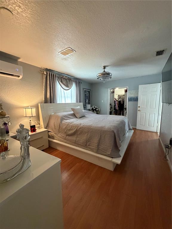 A bedroom features a white platform bed, wood-look flooring, and a walk-in closet — 4162 KINGSBRIDGE DRIVE, ORLANDO, FL