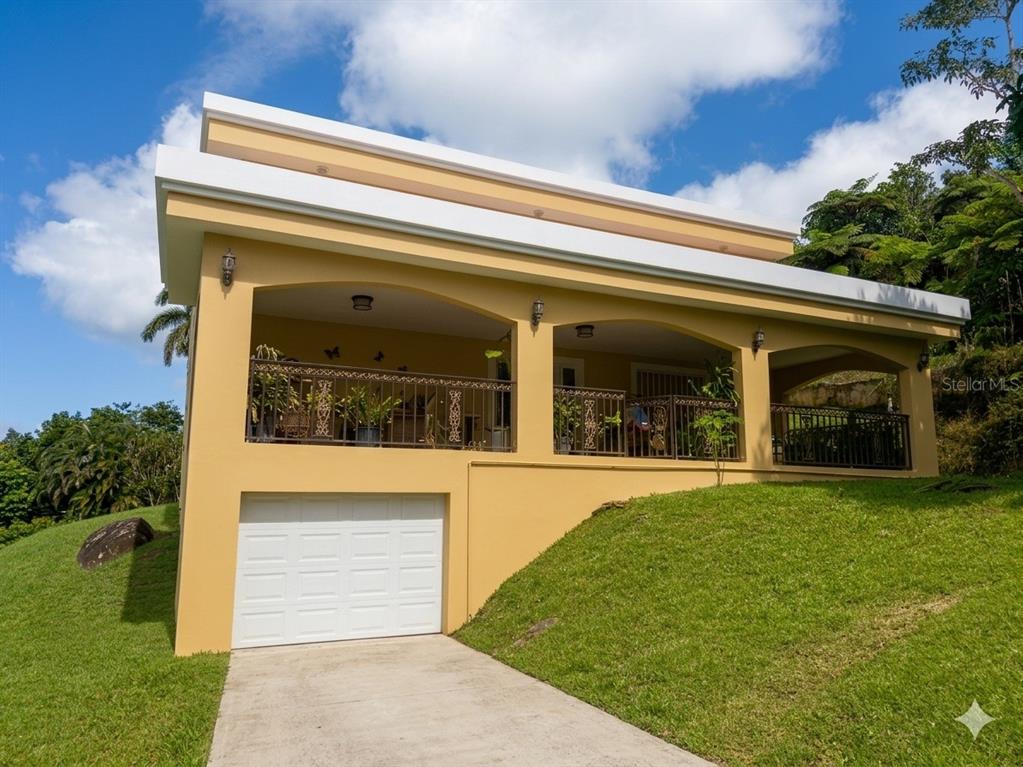A yellow house with a white garage door and a large covered balcony — Bo Beatriz Las Piñas FINCA MI RECREO  LOT 28, CAGUAS, PR