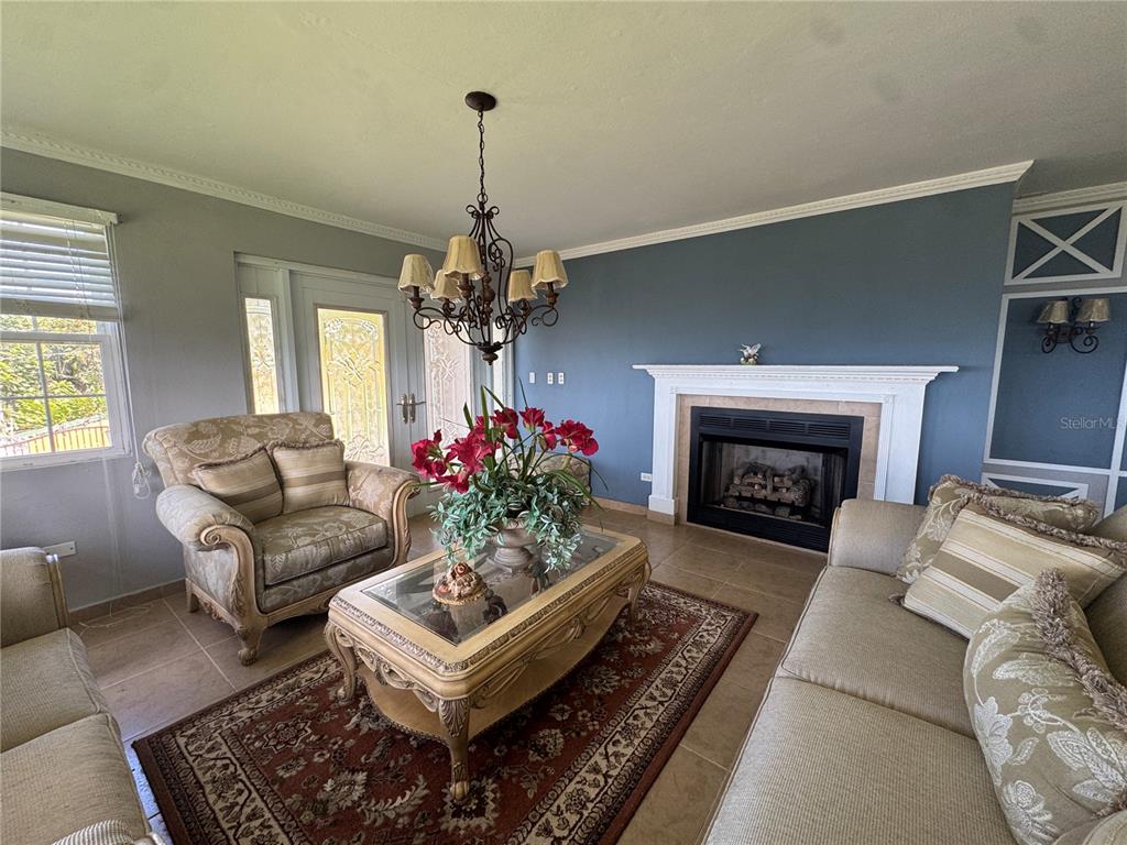 A living room features a fireplace, a chandelier, tile flooring, and traditional furniture — Bo Beatriz Las Piñas FINCA MI RECREO  LOT 28, CAGUAS, PR