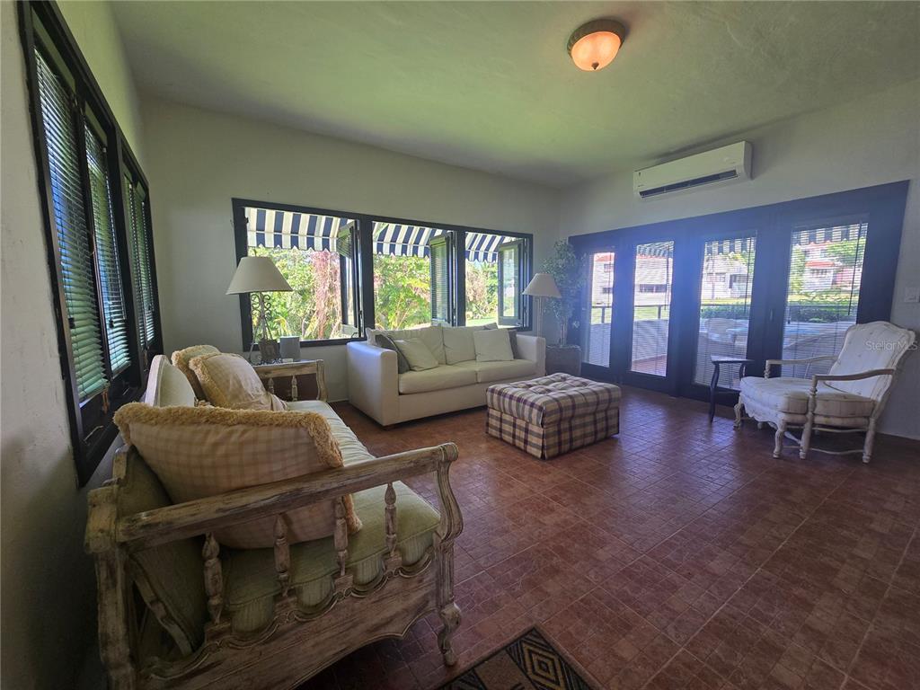 A sunroom features tile flooring, a white sofa, a wooden armchair, and large windows — Cluster 2, 40-B CLUSTER 2, RIO MAR, RIO GRANDE, PR