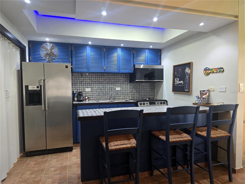 A kitchen features blue louvered cabinets, patterned tile backsplashes, stainless steel appliances, and a breakfast bar — Cluster 2, 40-B CLUSTER 2, RIO MAR, RIO GRANDE, PR
