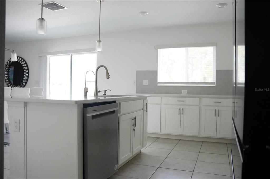 A kitchen features white cabinets, stainless steel appliances, a center island, and tile flooring — 16436 WINDING PRESERVE CIRCLE, CLERMONT, FL