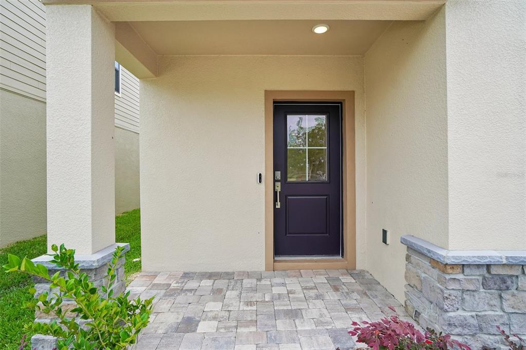 A covered front porch with stone accents leads to a dark door with a window — 3237 CUP DRIVE, LAKELAND, FL