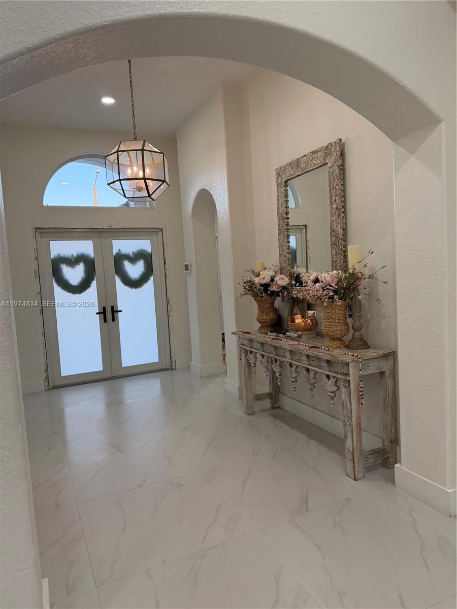 A bright entryway features a white arched doorway, tile flooring, and a rustic console table — 3744 SW 156th Ct, Miami FL 33185, MIAMI, FL
