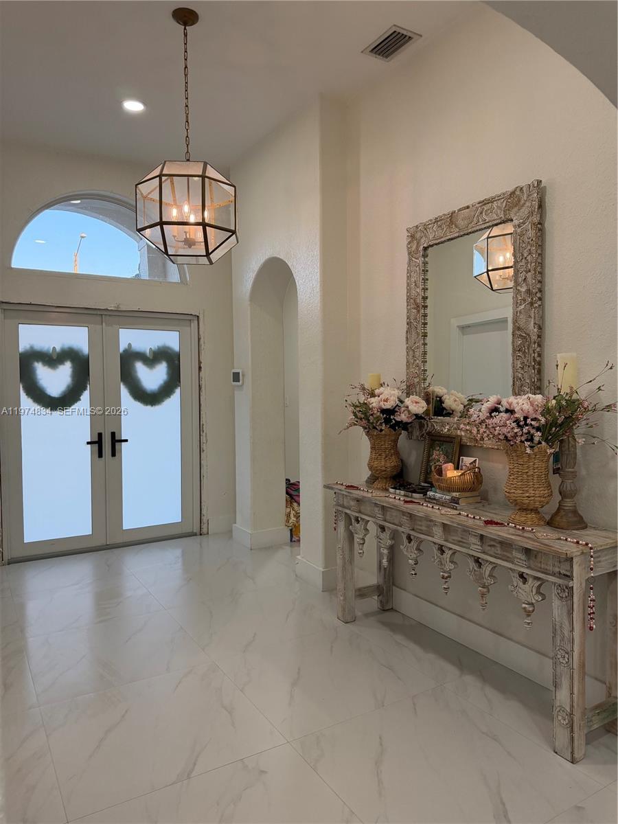 A bright entryway features white marble floors, a decorative console table, and double glass doors — 3744 SW 156th Ct, Miami FL 33185, MIAMI, FL