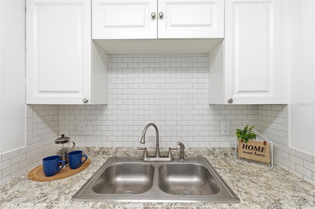 A kitchen sink area features white cabinets, a subway tile backsplash, and granite countertops — 2353 SHELLEY STREET UNIT 19, CLEARWATER, FL