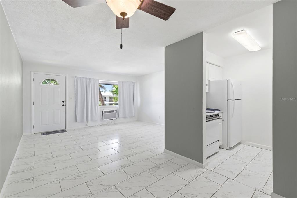 A living area with white tile floors leads to a small kitchen with white appliances — 2353 SHELLEY STREET UNIT 19, CLEARWATER, FL