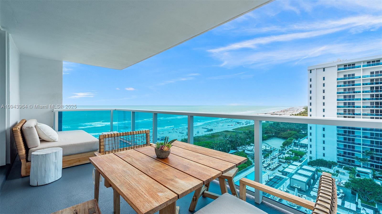 A balcony features a wooden table, seating, and a panoramic view of the ocean — 102 24th St # 1120, Miami Beach FL 33139, MIAMI BEACH, FL