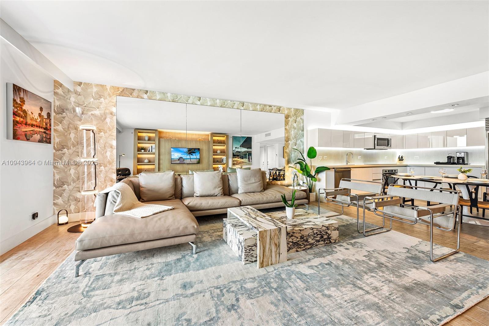 A modern living room features a large sectional sofa, marble coffee table, and mirrored wall — 102 24th St # 1120, Miami Beach FL 33139, MIAMI BEACH, FL