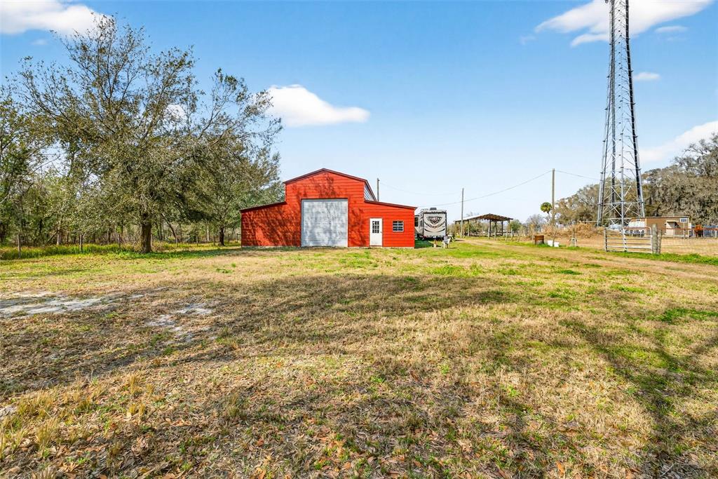 A red barn with a large garage door stands in a grassy field — 4361 COOPER ROAD, PLANT CITY, FL