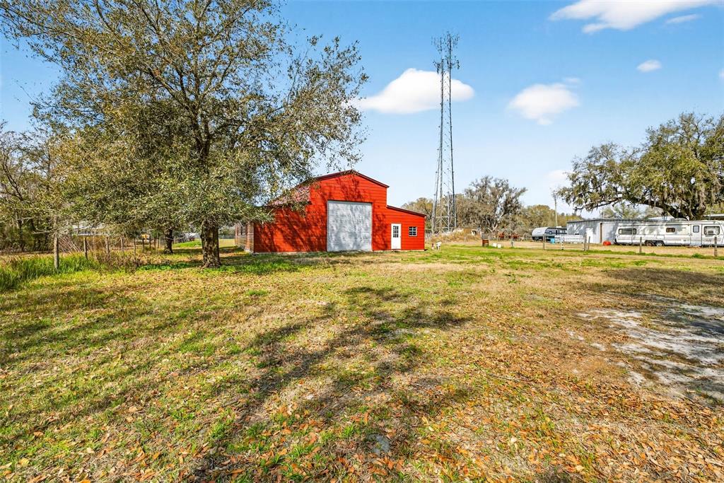 A red barn stands in a grassy field near a tall communication tower and trailer — 4361 COOPER ROAD, PLANT CITY, FL