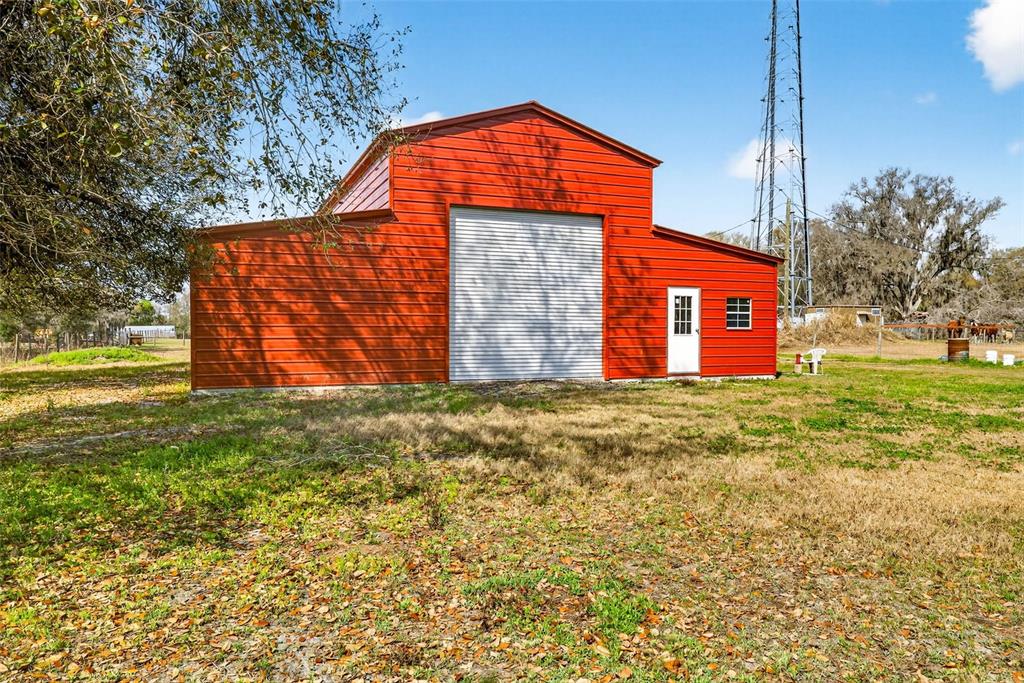 A red metal barn with a roll-up garage door and a side entry door — 4361 COOPER ROAD, PLANT CITY, FL