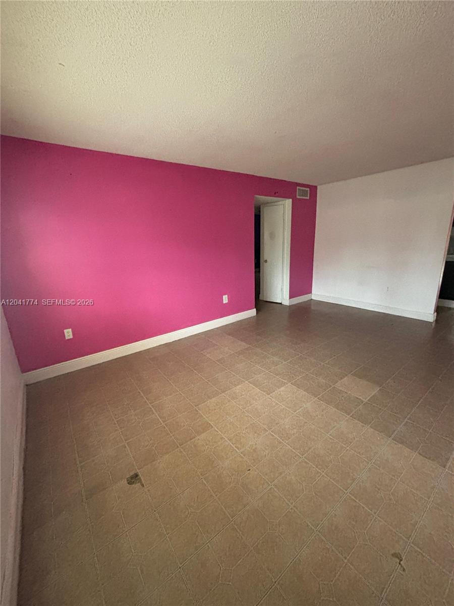 An empty room features a bright pink accent wall, white walls, and tiled flooring — 5325 Curry Ford Rd # A104, Orlando FL 32812, ORLANDO, FL