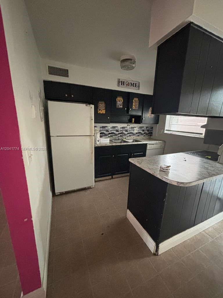 A kitchen features black cabinets, a white refrigerator, and a light-colored countertop — 5325 Curry Ford Rd # A104, Orlando FL 32812, ORLANDO, FL