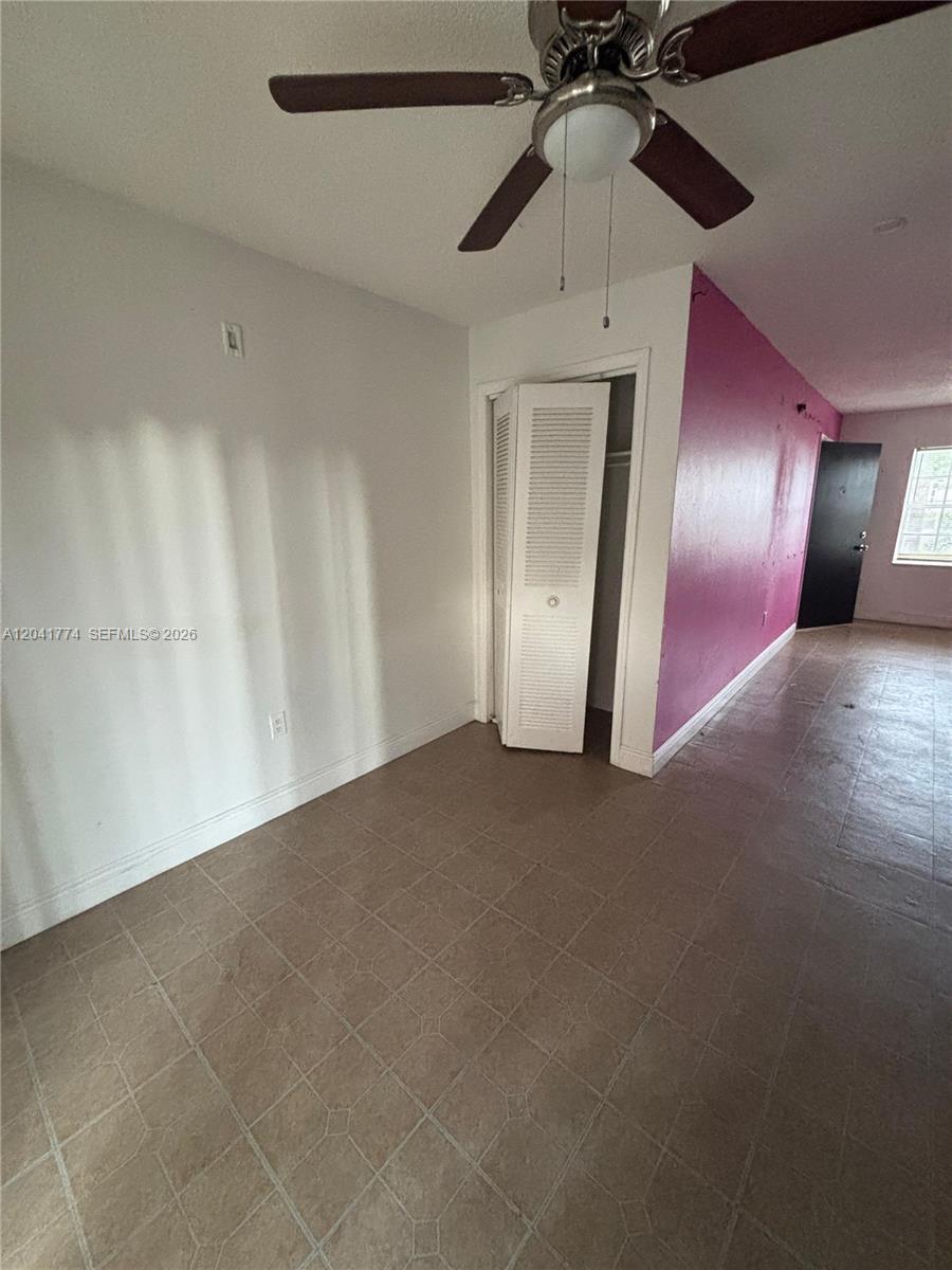 This room features tiled flooring, a ceiling fan, a closet with louvered doors, and pink walls — 5325 Curry Ford Rd # A104, Orlando FL 32812, ORLANDO, FL