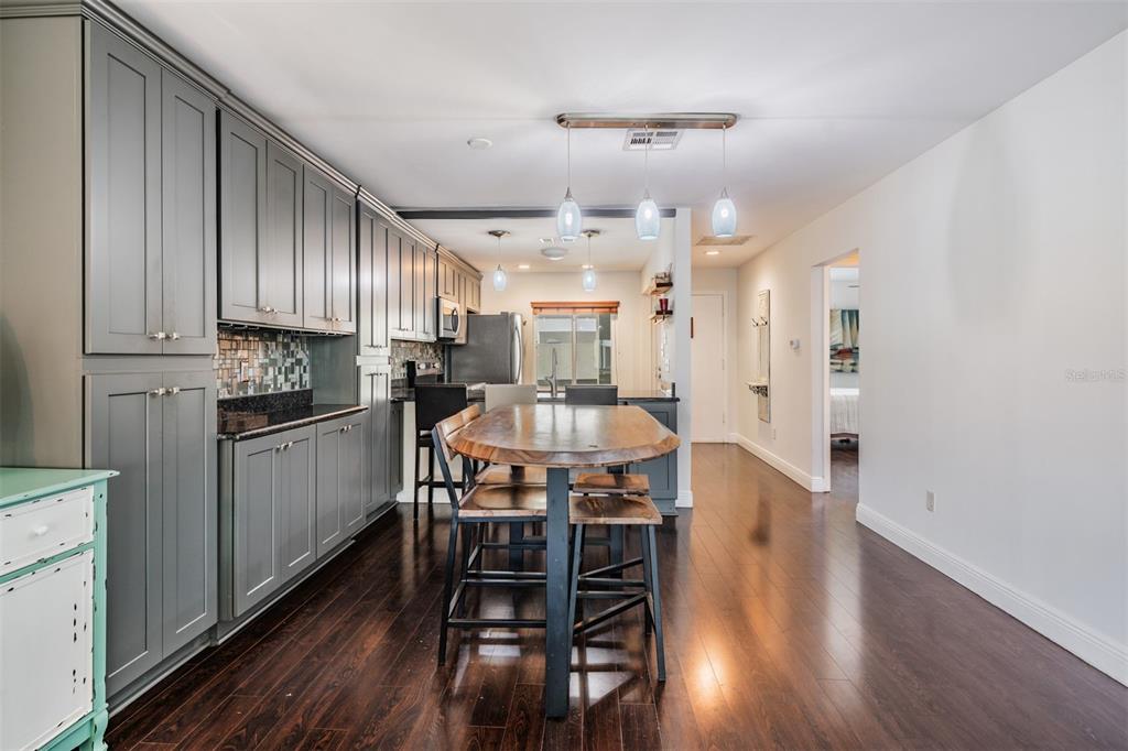 A kitchen with gray cabinetry, dark wood flooring, and a central wooden dining table — 637 DRAKE LANE N, DUNEDIN, FL