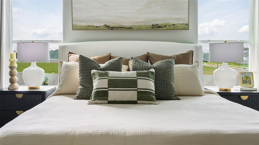 A bedroom features a white upholstered headboard, textured bedding, and two bedside lamps — 33653 NOBLE CREEK PLACE, DADE CITY, FL