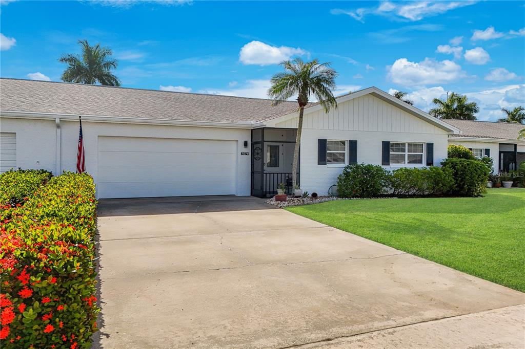 A white single-story house with a two-car garage, a screened entryway, and a front lawn — 7079 CEDARHURST DRIVE, FORT MYERS, FL