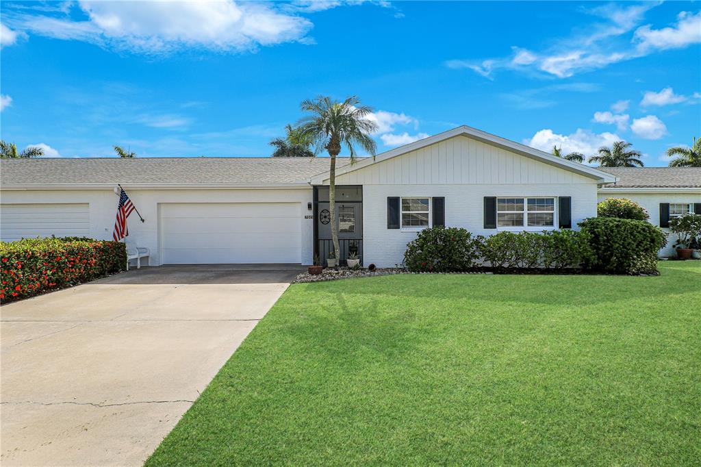 A single-story white brick house features a two-car garage, a front lawn, and palm trees — 7079 CEDARHURST DRIVE, FORT MYERS, FL