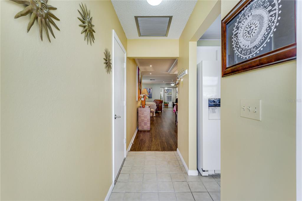 A tiled entryway leads into a wood-floored living area with yellow walls and sun decor — 7079 CEDARHURST DRIVE, FORT MYERS, FL