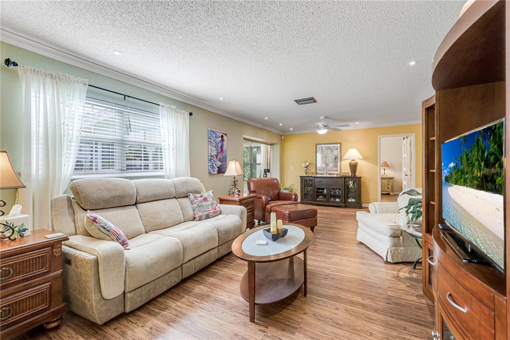 A living room features a beige sofa, leather armchair, wood flooring, and a television — 7079 CEDARHURST DRIVE, FORT MYERS, FL
