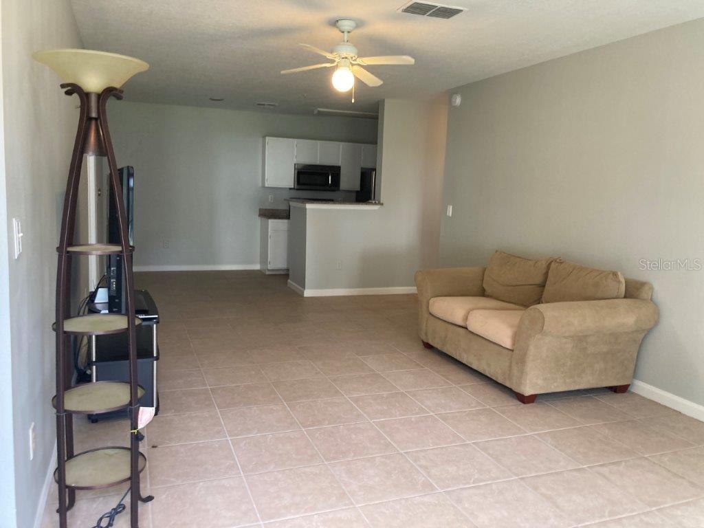 A living room with tile flooring, a beige sofa, and an open kitchen in back — 4352 S KIRKMAN ROAD UNIT 1211, ORLANDO, FL