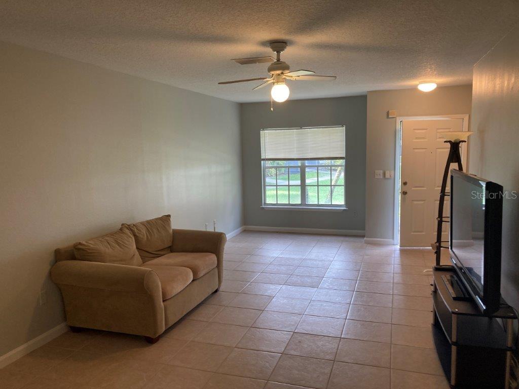 A living room features light-colored tile flooring, a beige sofa, and a ceiling fan — 4352 S KIRKMAN ROAD UNIT 1211, ORLANDO, FL