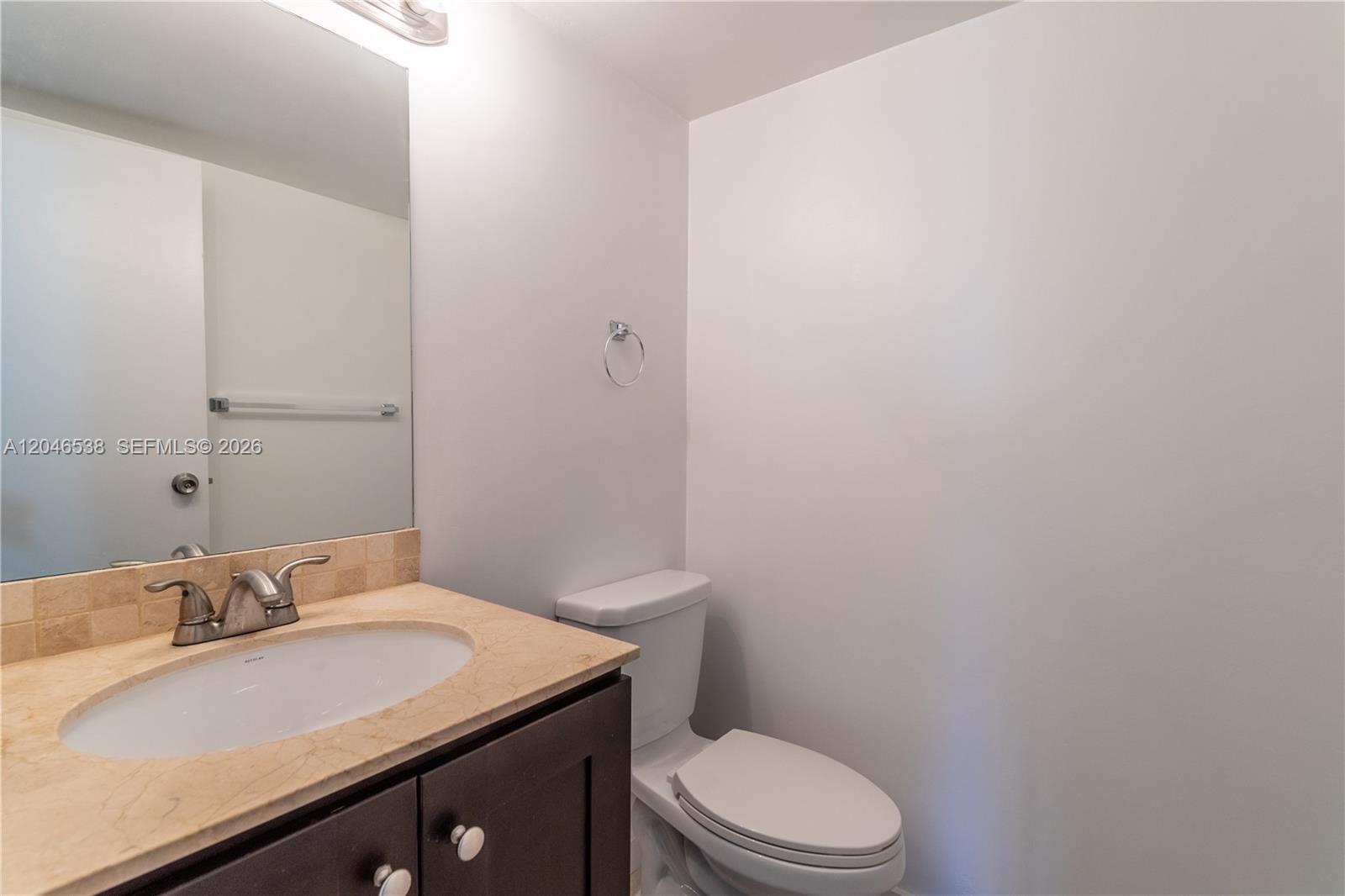 A bathroom features a dark vanity with a stone countertop, a mirror, and a toilet — 1000 Parkview Dr # 302, Hallandale Beach FL 33009, HALLANDALE BEACH, FL