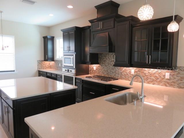 A kitchen features dark wood cabinets, light quartz countertops, and a large central island — 5827 TITLE ROW DRIVE, BRADENTON, FL