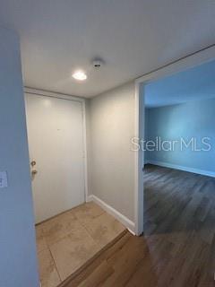 An entryway with tile flooring leads to a doorway opening into a room with wood floors — 455 ALT 19 S UNIT 121, PALM HARBOR, FL