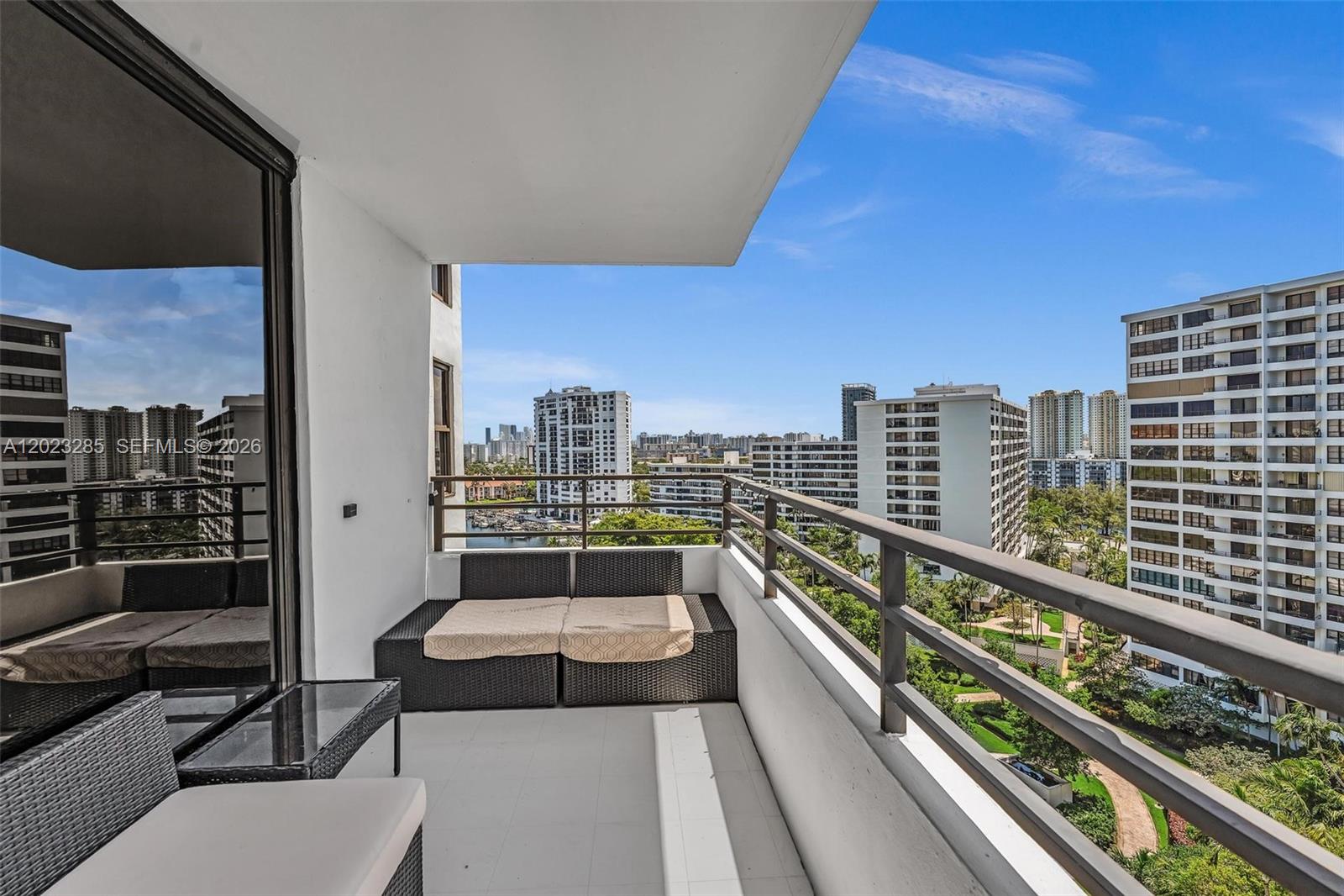 A balcony with outdoor furniture overlooks a marina and surrounding high-rise apartment buildings — 2500 Parkview Dr # 1514, Hallandale Beach FL 33009, HALLANDALE BEACH, FL
