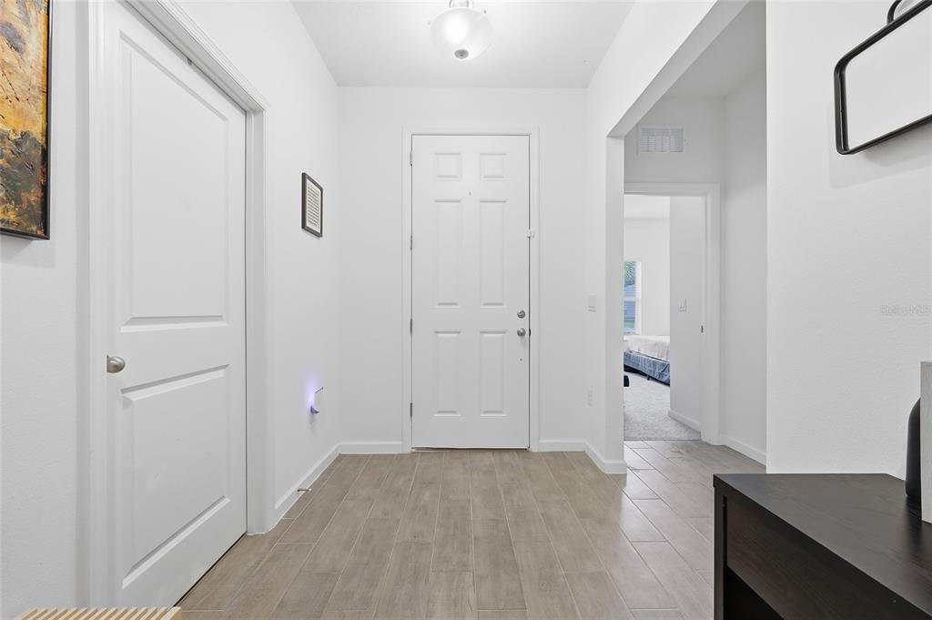 A bright entryway features light-colored tile flooring, a white front door, and a hallway entrance — 9068 CAPE COD ROAD, DELAND, FL