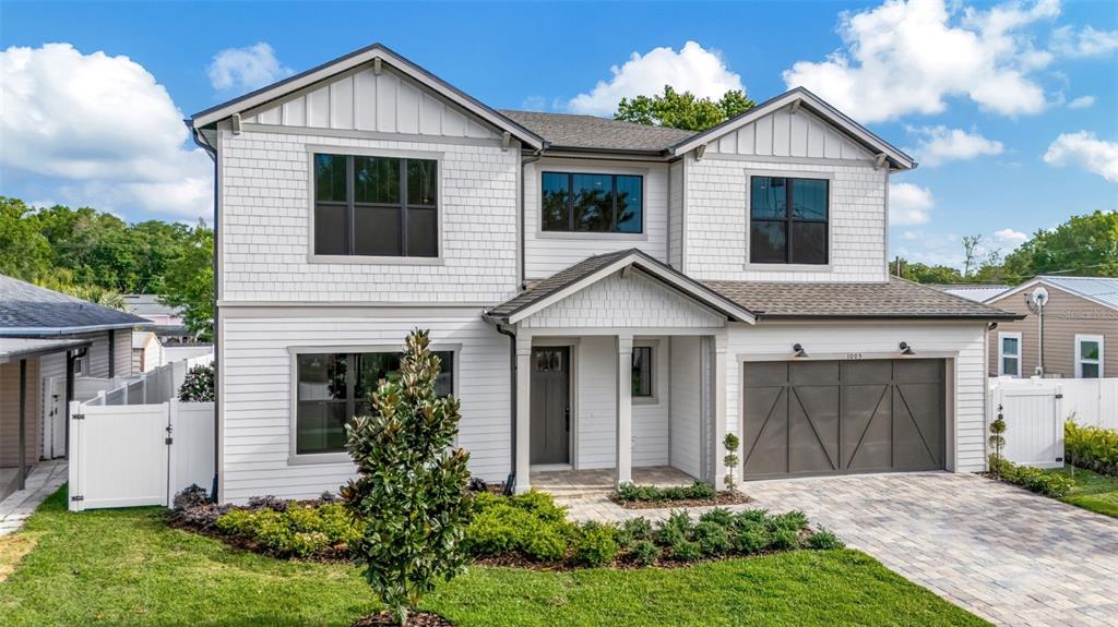A two-story house with white siding, a gray garage door, and a paved driveway — 3608 W WALLACE AVENUE, TAMPA, FL