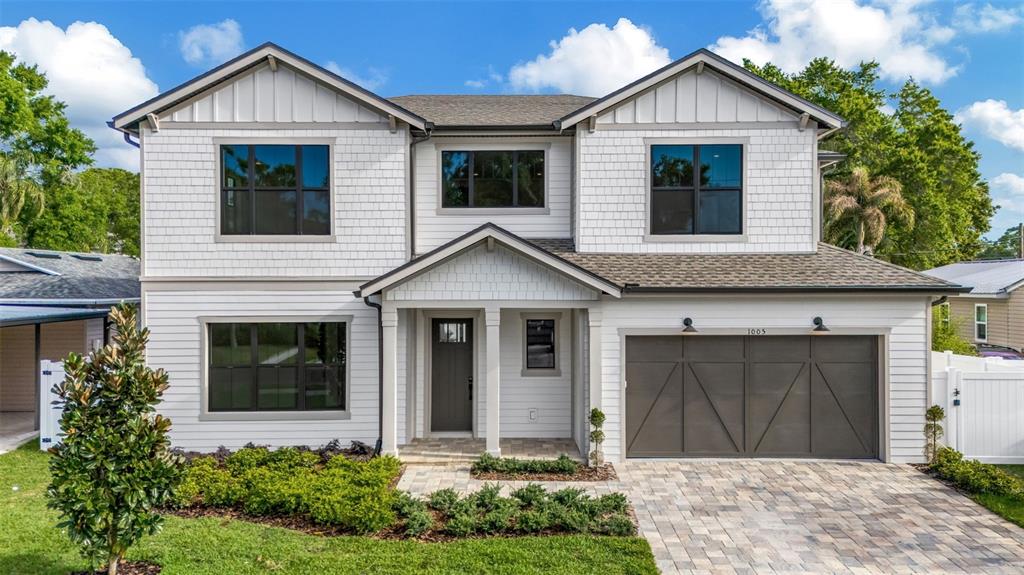 A two-story house with white siding, a dark garage door, and a paved driveway — 3608 W WALLACE AVENUE, TAMPA, FL