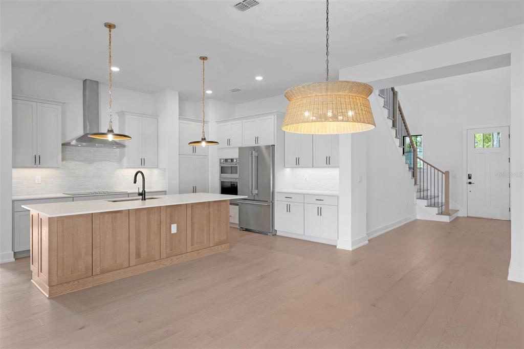 A modern kitchen features light wood cabinetry on the island, white upper cabinets, and stainless appliances — 3608 W WALLACE AVENUE, TAMPA, FL