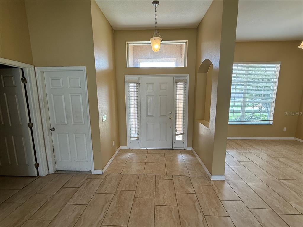 A tiled entryway features a high ceiling, a front door with sidelights, and a pendant light — 7101 WHITE TRILLIUM CIRCLE, ORLANDO, FL