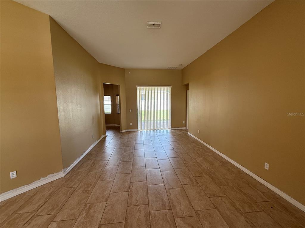 An empty room with tan walls, tile flooring, and a sliding glass door — 7101 WHITE TRILLIUM CIRCLE, ORLANDO, FL