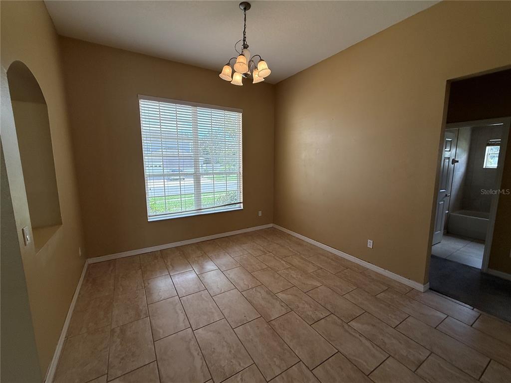 An empty room with tan walls, tile flooring, a chandelier, and a window with blinds — 7101 WHITE TRILLIUM CIRCLE, ORLANDO, FL