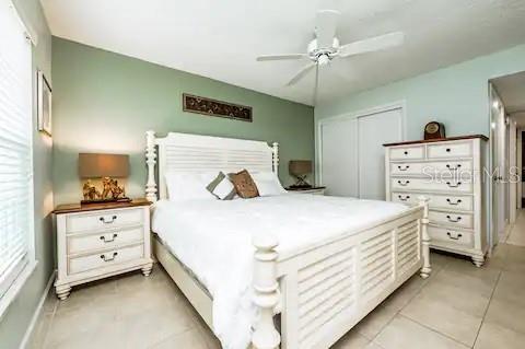 A bedroom features a white bed frame, matching dresser, sage green walls, and a ceiling fan — 3801 S ATLANTIC AVENUE UNIT 107, NEW SMYRNA BEACH, FL