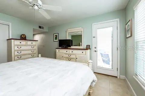 A bedroom features a white dresser, a television on a console, and a glass-paned door — 3801 S ATLANTIC AVENUE UNIT 107, NEW SMYRNA BEACH, FL