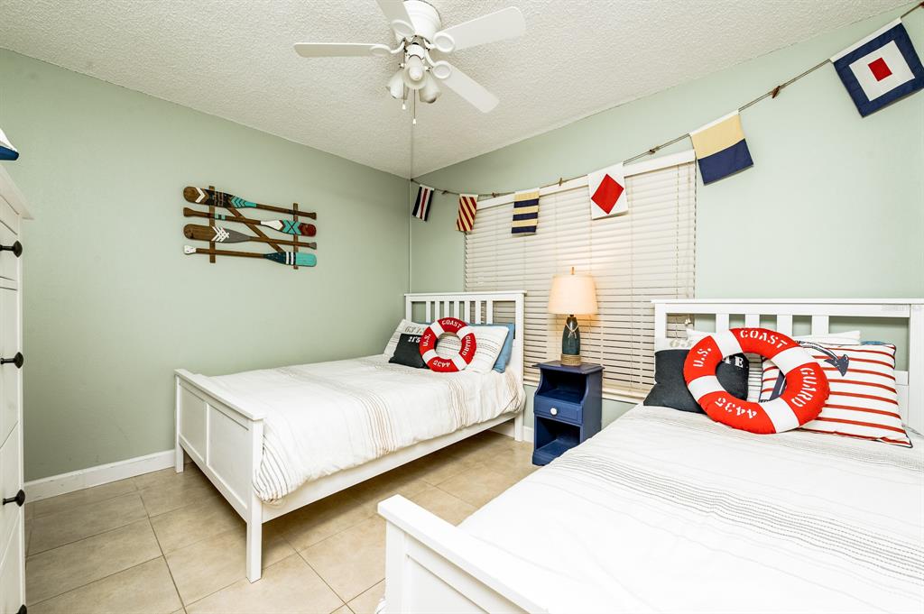 A bedroom features two white beds, nautical-themed decor, and light green walls — 3801 S ATLANTIC AVENUE UNIT 107, NEW SMYRNA BEACH, FL