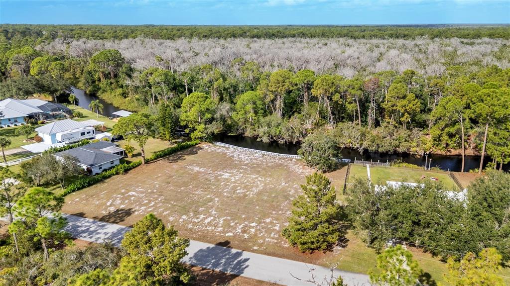 An aerial view shows a vacant, cleared residential lot bordering a canal and wooded area — 1100 SYCAMORE STREET, LAKE PLACID, FL